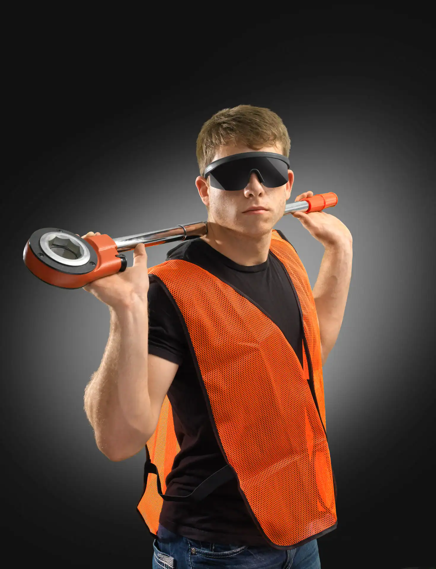 A man in a black shirt, orange safety vest, and dark safety glasses poses with a large pipe wrench across his shoulders—showcasing skilled professionalism for photography services in Harris County,TX, against a dark gradient background.