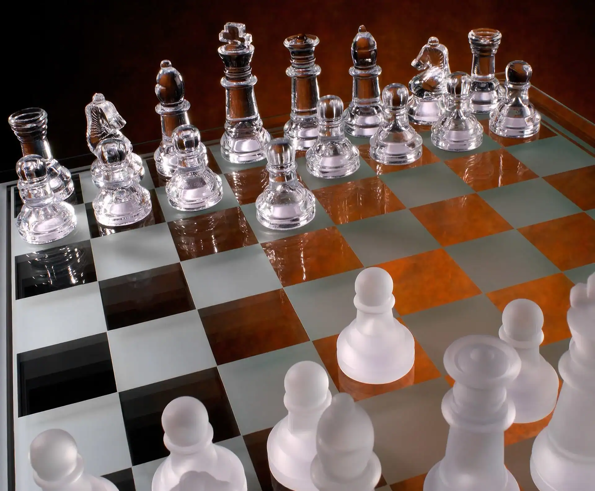 A close-up view of a glass chessboard with clear and frosted pieces, ready for a game. Warm lighting highlights the shiny textures&mdash;perfect for those seeking photography services in Harris County, TX to capture elegant details.