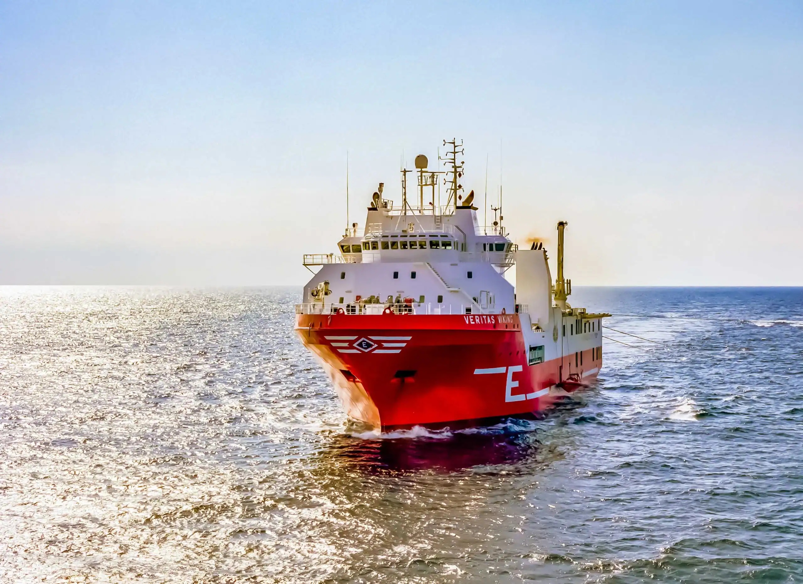 A large red and white ship sails on a sparkling blue sea under a clear TX sky. The vessel is heading toward the camera, with visible antennas and equipment—perfect for photography services Harris County enthusiasts.