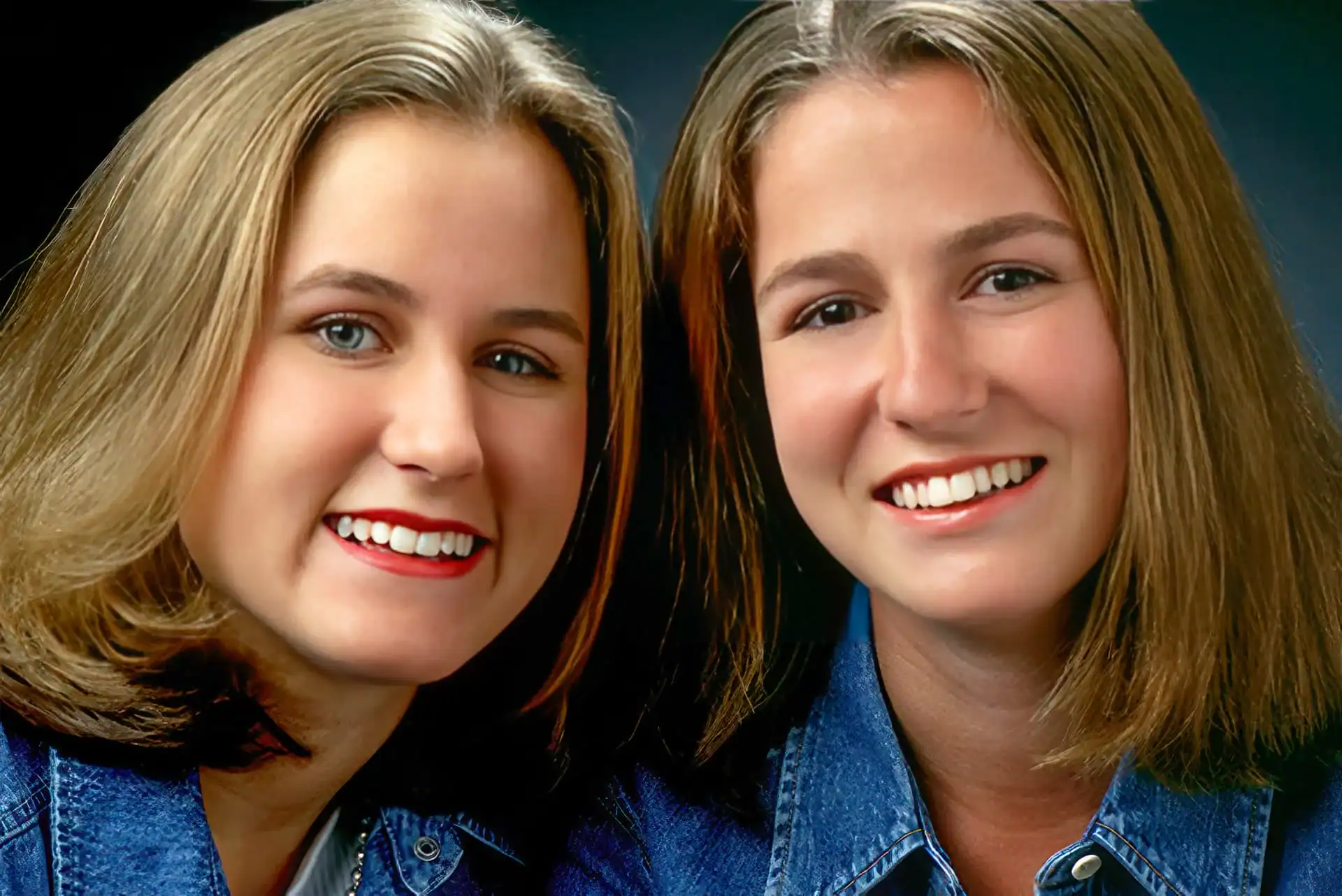 Two young women with light brown hair, smiling and wearing blue denim jackets, pose closely together against a dark background&mdash;capturing a timeless moment with photography services Harris County, TX.